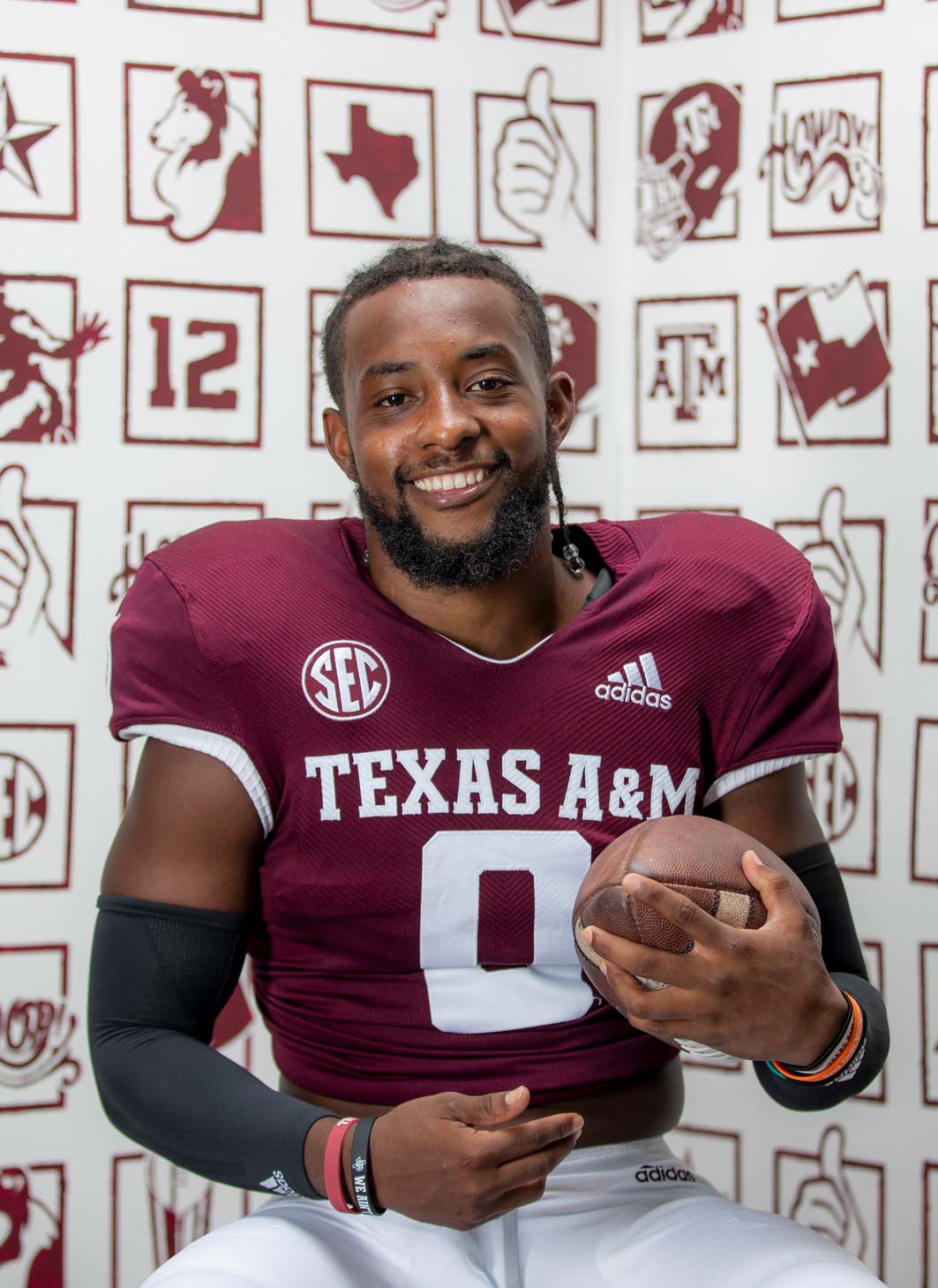 Ainias Smith in football pads posing with football