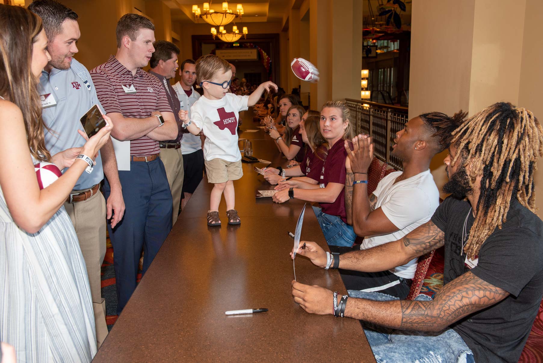 Camron Buckley sitting at a table with other students catching a ball from a child
