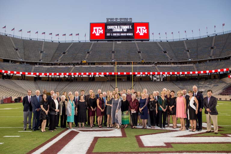 Carolyn and Tommie Lohman posing with a group of others on the field
