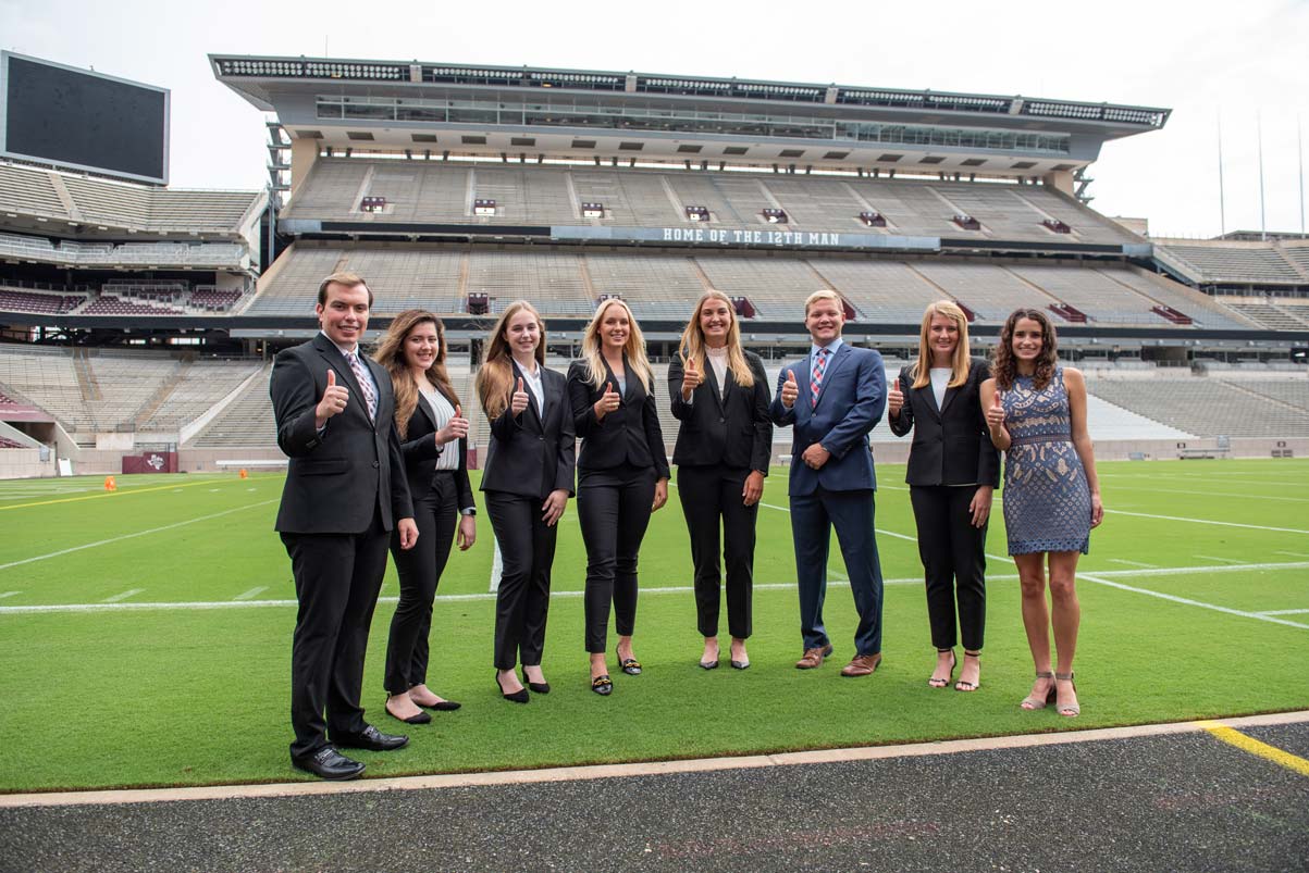 The Collegiate Council on the football field giving thumbs up