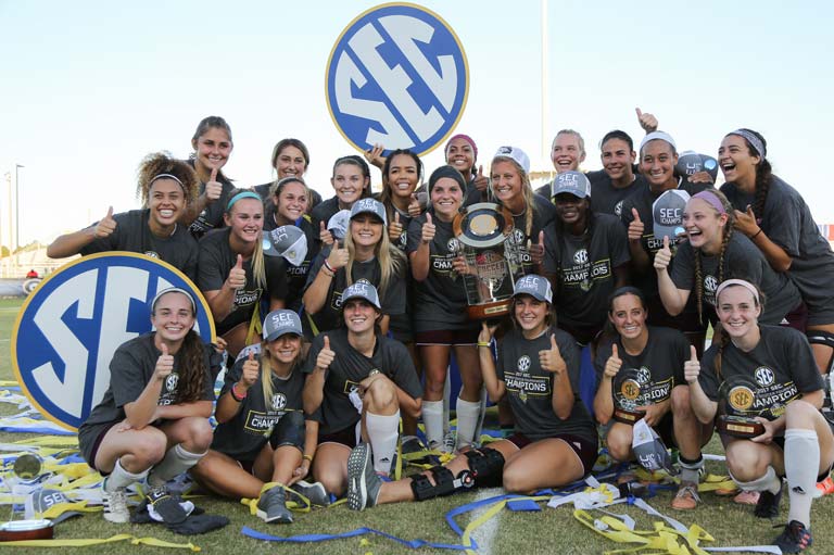 The women's soccer team posing with SEC signs
