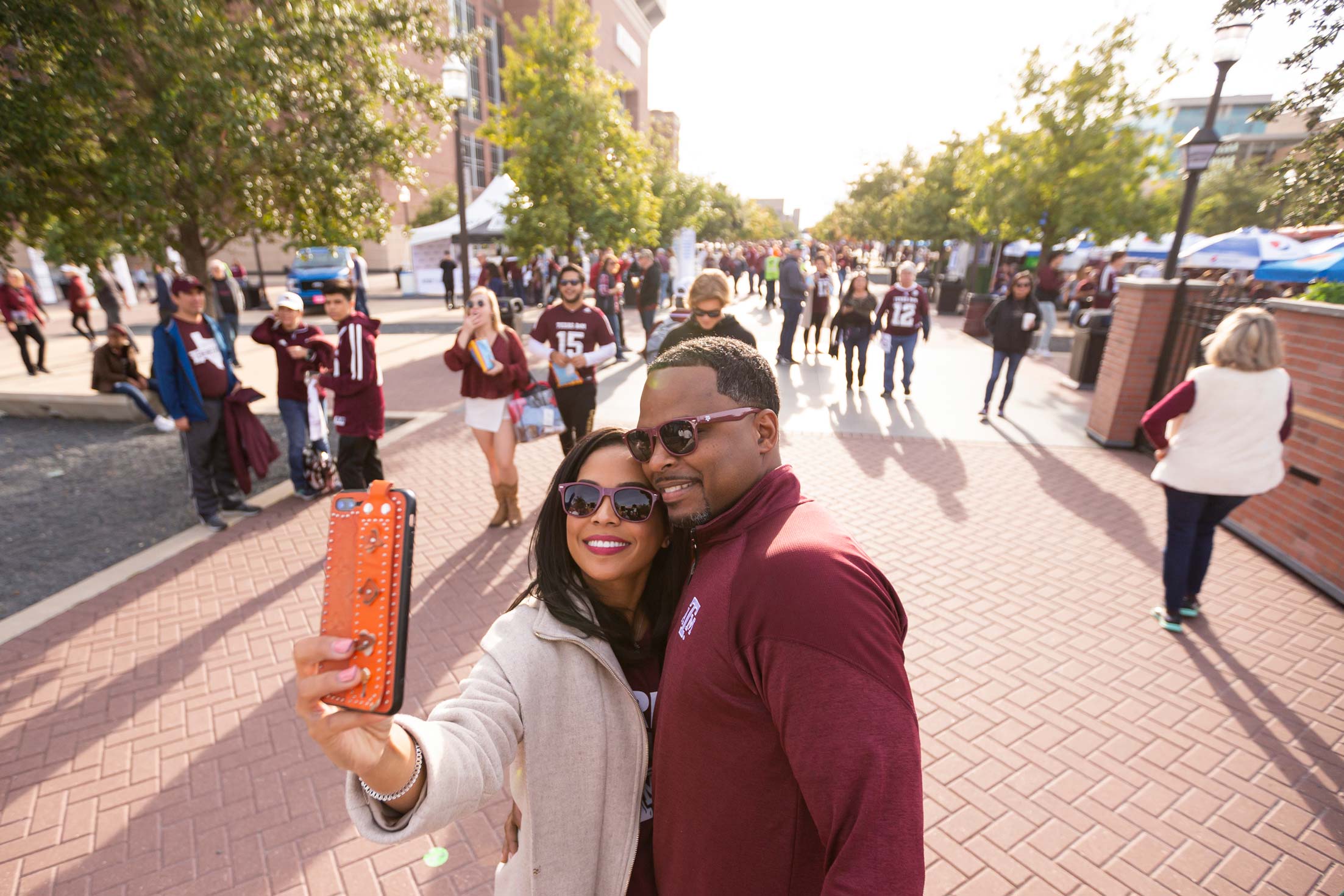 A couple taking a selfie outside of the stadium with other people in the background