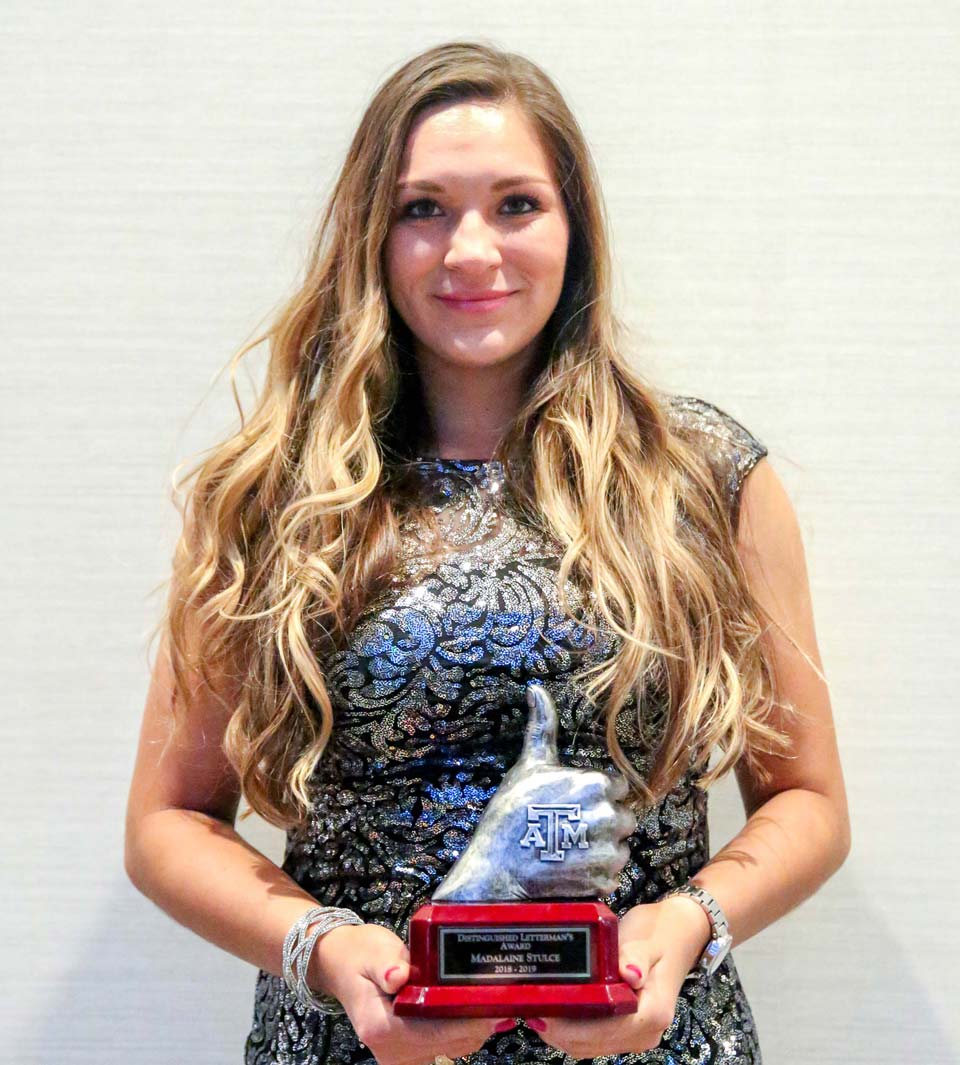 A student-athlete posing with an award