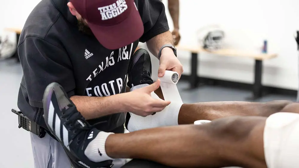 a trainer wrapping a player's ankle